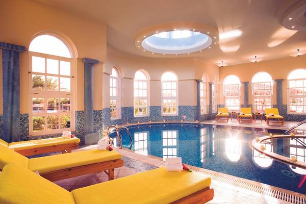 Das Schwimmbad im Chedi El Gouna Hotel mit blauen Wänden, gelben Liegen und einem runden Pool.
