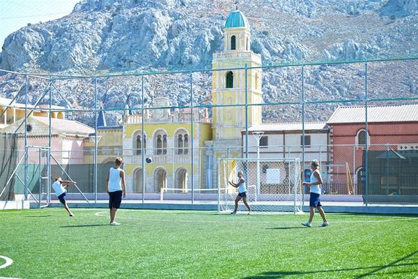 Fussballspieler spielen auf einem Fussballplatz im Freien vor einem historischen Gebäude.
