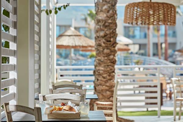 Außenterrasse des Atlantica Aegean Blue Resorts mit einem Tisch, auf dem Essen serviert wird.