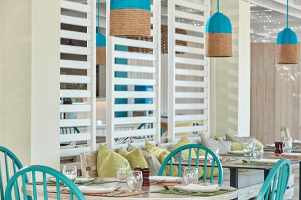 Restaurant Innenraum des Atlantica Aegean Blue Resorts mit blauen Stühlen und Tischen.