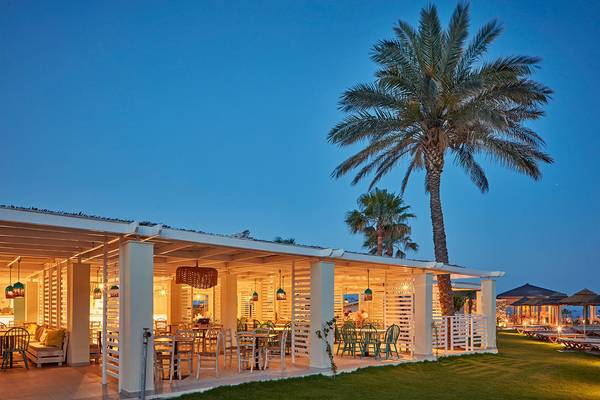 Abendliche Terrasse des Atlantica Aegean Blue Resorts mit Palmen und illuminierten Tischen