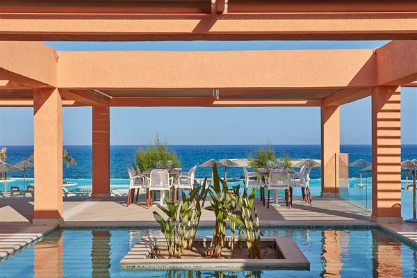 Poolbereich mit Sonnenliegen und Tisch im Atlantica Aegean Blue Resort.