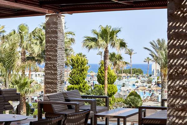 Terrasse des Atlantica Aegean Blue Resorts mit Blick auf einen Pool und das Meer.