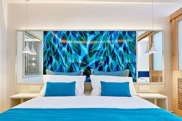 Bett im Zimmer im Atlantica Aegean Blue Resort mit blauem Blattmuster an der Wand