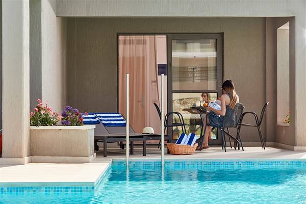 Frau sitzt auf der Terrasse und liest ein Buch am Swimmingpool des Atlantica Aegean Blue Resorts
