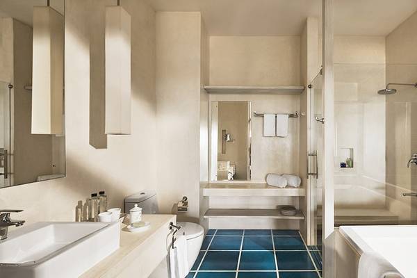 Innenansicht des Badezimmers im Jetwing Blue Hotel mit blauen Kacheln, einer Badewanne, einer Dusche und einem Waschbecken.