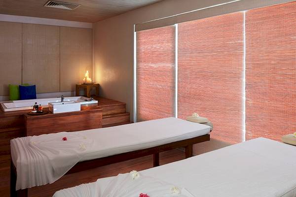 Behandlungsraum im Jetwing Blue Spa mit zwei Massageliegen und einem Badewannenbereich.