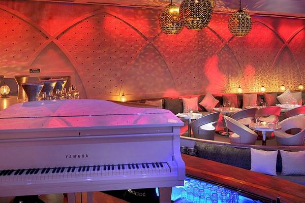 Innenbereich des Sofitel Marrakech Lounge & Spa mit einem weißen Klavier und roten Beleuchtung.