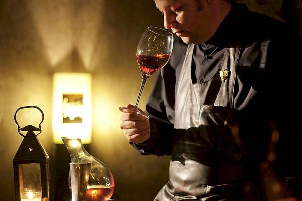 Mann der Sofitel Marrakech Lounge & Spa Wein kostet in einem dunklen Raum