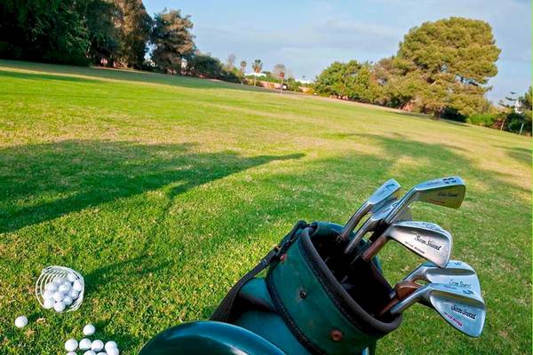 Golfplatz mit einem Golfbag, Schlägern und Bällen auf dem Rasen.