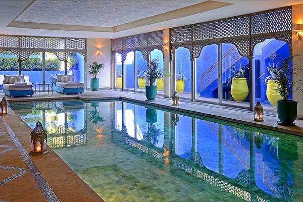 Pool im Sofitel Marrakech Lounge & Spa mit blauen Wänden und grünen Pflanzen.