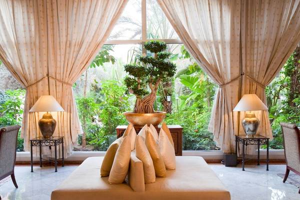 Sofa mit Kissen vor einem großen Fenster im Sofitel Marrakech Lounge & Spa Hotel.
