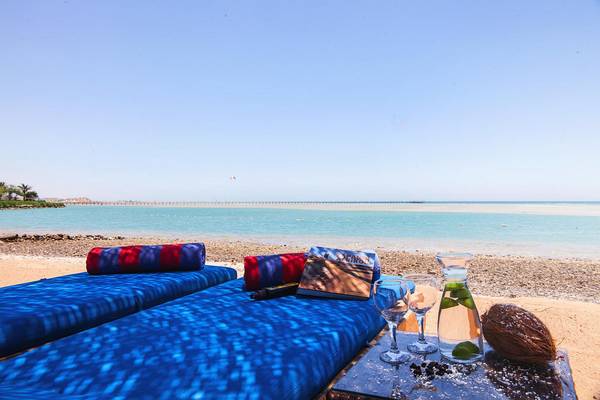 Strand-Lounge-Betten im Chedi El Gouna mit Blick auf das Meer und einen Kokosnuss-Drink.