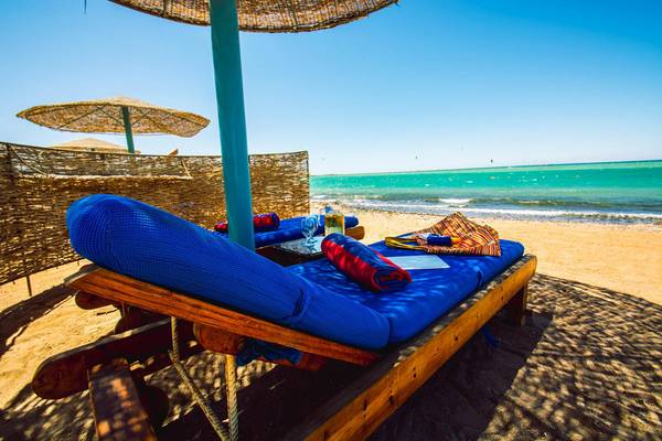 Zwei blaue Sonnenliegen am Strand des Chedi El Gouna mit einem Tisch und einer offenen Flasche.