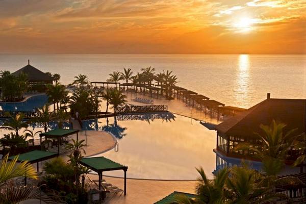 Guyarmimina Princess Hotel mit Pool und Meerblick bei Sonnenuntergang.