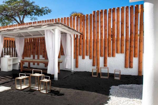 Außenbereich des Guayarmina Princess Hotels mit einem Pavillon, weißen Vorhängen und Holzzaun.