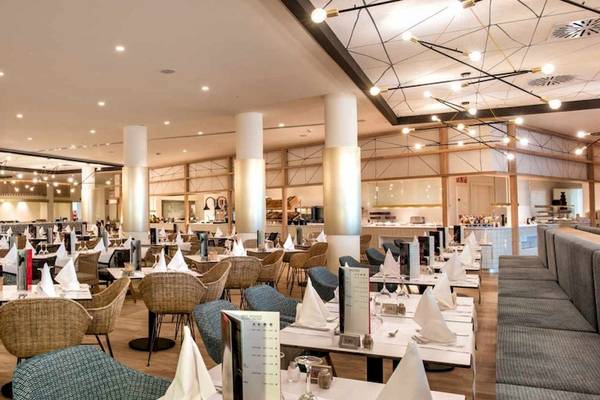 Innenbereich des Restaurants im Guayarmina Princess Hotel mit runden Tischen und Stühlen, dekorativen Lichtern und Holzboden.