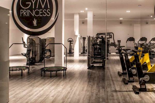 Innenansicht des Gyms der Guayarmina Princess mit diversen Fitnessgeräten und einem Holzboden.