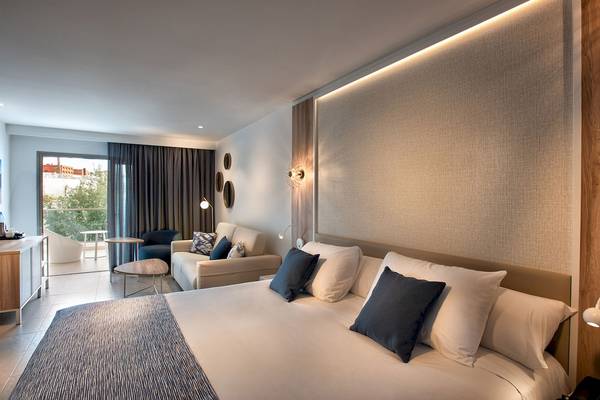 Guyarmiina Princess Hotel Schlafzimmer mit Doppelbett, Kissen, Couch und Glastür.