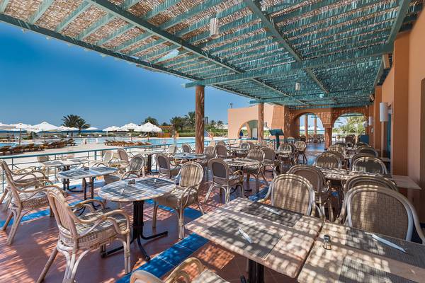 Restaurantterrasse im Chedi El Gouna Hotel mit Tischen und Stühlen unter einem grünen Baldachin