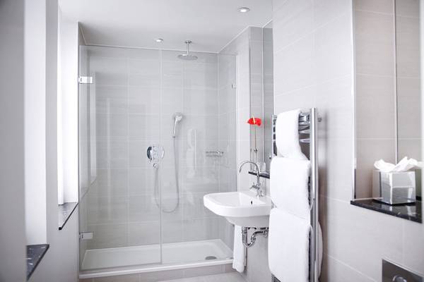 Ein kleines Badezimmer mit einer Glasdusche und einem Waschbecken neben einem Handtuchhalter.