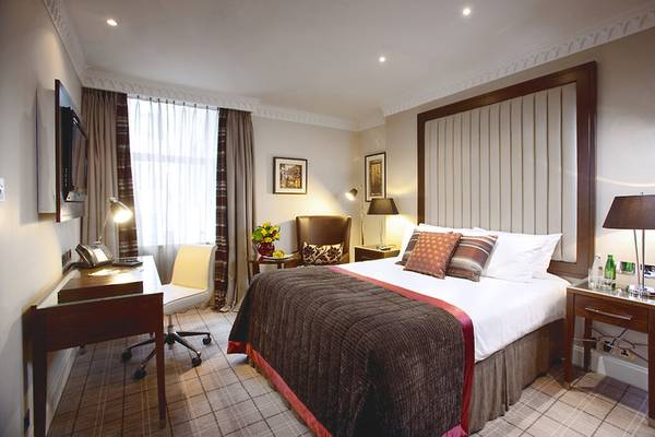 Schlafzimmer im Clermont Hotel, Charing Cross mit einem großen Bett, Schreibtisch, Stühlen und Lampen.