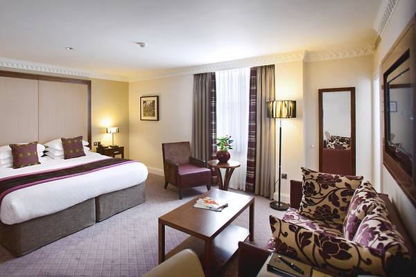 Hotelzimmer im Clermont Hotel, Charing Cross mit großem Bett, Sesseln, Tisch und Lampe.