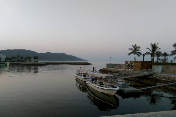 Zwei Boote am Kai des Sifawy Boutique Hotels mit Blick auf das Wasser und Berge im Hintergrund.