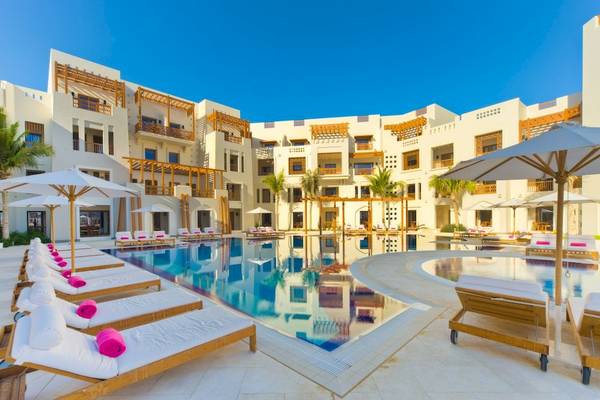 Außenbereich des Sifawy Boutique Hotels mit Swimmingpool, Sonnenliegen und Sonnenschirmen.