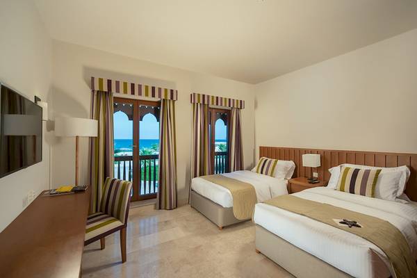 Zimmer im Sifawy Boutique Hotel mit zwei Betten, Meerblick und modernen Möbeln.