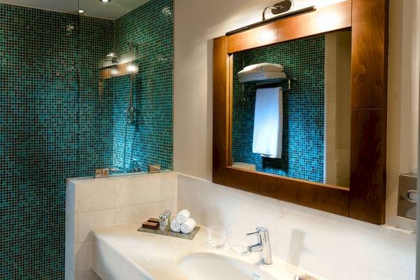 Badezimmer im Sifawy Boutique Hotel mit blauen Fliesen und einem großen Spiegel.