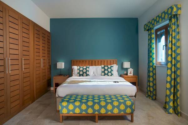 Schlafzimmer im Sifawy Boutique Hotel mit blauer Wand, Bett, Nachttischen und Holzschrank