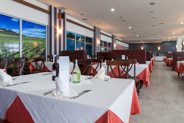 Restaurant im Sol Luna Bay All Inclusive Hotel mit roten und weißen Tischdecken und gedeckten Tischen.