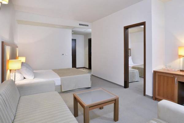 Ein modernes Hotelzimmer im Sol Luna Bay All Inclusive mit Bett, Schreibtisch, Fernseher und Möbeln.