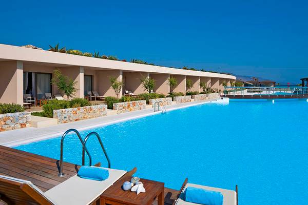 Außenpool im Giannoulis Cavo Spada Sports & Leisure Resort mit Sonnenliegen und Ausblick aufs Meer.