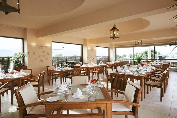 Innenansicht des Speisesaals im Giannoulis Cavo Spada Sport & Freizeit Resort mit gedeckten Tischen und Stühlen.