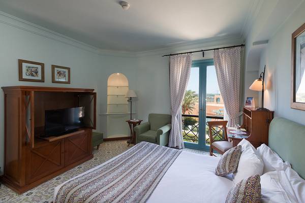 Hotelzimmer im The Chedi El Gouna mit Fernseher, Bett und Möbeln.
