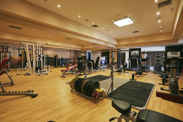 Das Fitnessstudio im Giannoulis Cavo Spada Sports & Leisure Resort mit verschiedenen Trainingsgeräten und einer Person auf einem Laufband.