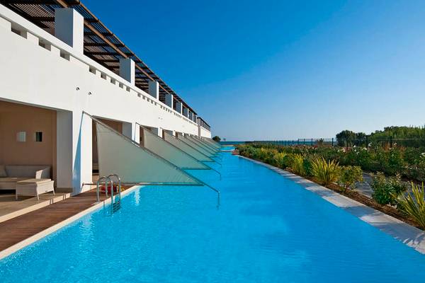 Außenpool des Giannoulis Cavo Spada Sports & Leisure Resort mit weißen Gebäuden und blauem Wasser