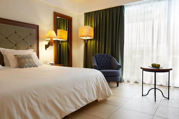 Schlafzimmer im Giannoulis Cavo Spada Sports & Leisure Resort mit Doppelbett, Nachttisch, Stuhl und Lampen.