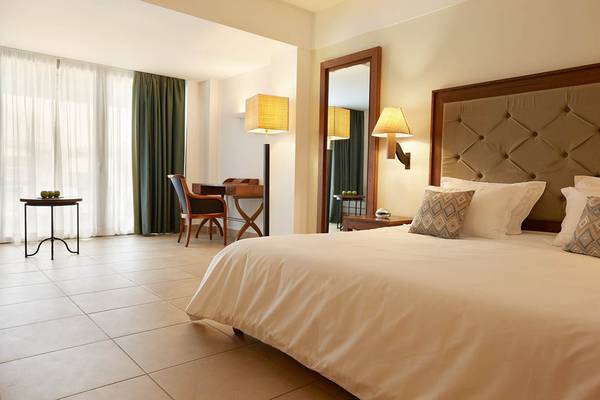 Innenansicht eines Hotelzimmers im Giannoulis Cavo Spada Sports & Leisure Resort mit Bett, Schreibtisch und Spiegel.