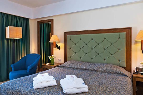 Hotelzimmer im Giannoulis Cavo Spada Sports & Leisure Resort mit Bett, Kissen, Bademäntel, Nachttisch und Lampen
