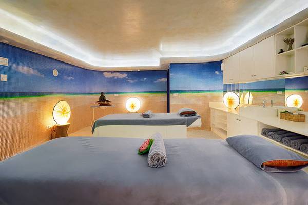 Behandlungsraum im Bull Costa Canaria & Spa mit zwei Massageliegen und Strandmotiven an den Wänden.