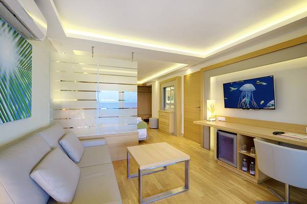 Inneneinrichtung eines Zimmers im Bull Costa Canaria & Spa Hotel mit Sofa, Couchtisch, Fernseher und Schreibtisch.