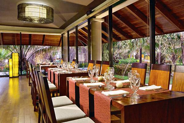 Innenbereich des Westin Reserva Conchal Golf Resorts mit gedeckten Esstischen und Blick auf den Garten