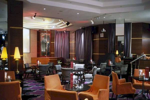 Loungebereich des Hilton Salalah Resorts mit braunen Stühlen und Tischen, braunen Vorhängen und Deckenlampen.