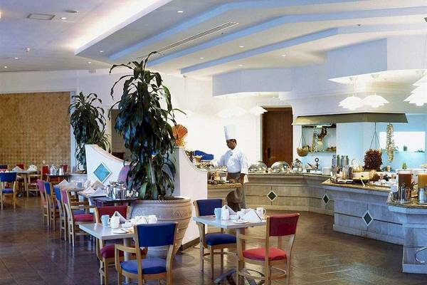 Innenansicht des Restaurants im Hilton Salalah Resort mit Tischen, Stühlen und einem Koch.