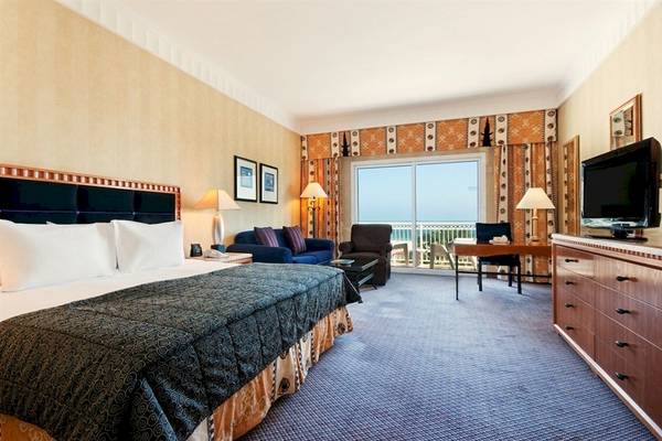 Hotelzimmer im Hilton Salalah Resort mit Bett, Sofa, Schreibtisch und Meerblick.