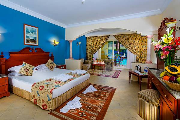 Hotelzimmer mit blauen Wänden, einem großen Bett, weichen Kissen und einem Poolblick.