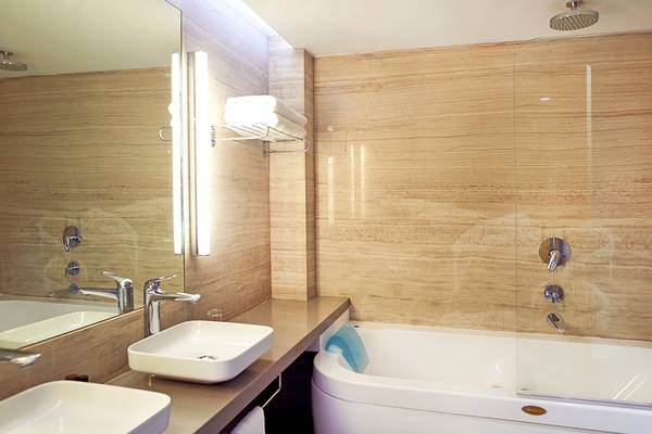 Badezimmer im Sunrise Beach Hotel in Zypern mit einer Badewanne und zwei Waschbecken.